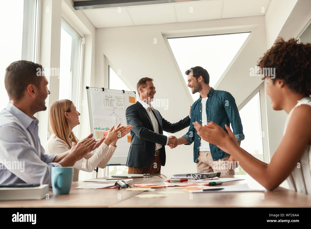 Für unser Team zwei freundliche Kollegen die Hände schütteln und lächelnd, während Sie an einer Konferenz im modernen Büro willkommen. Teamarbeit Stockfoto