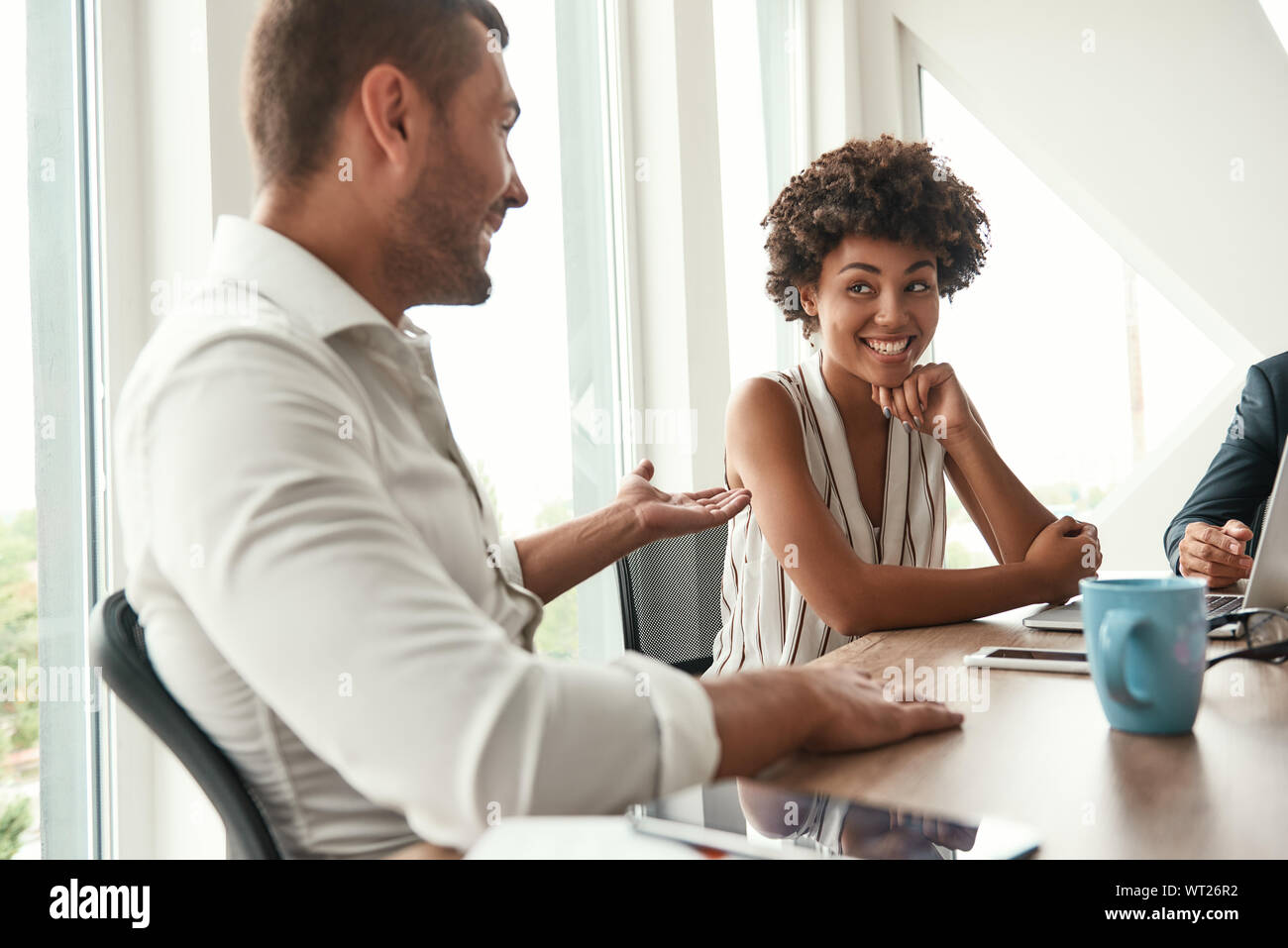 Austausch neuer Ideen. Junger Mann im weißen Hemd etwas diskutieren mit schönen afro-amerikanische Frau beim Sitzen im business meeting im modernen Büro. Brainstorming Stockfoto