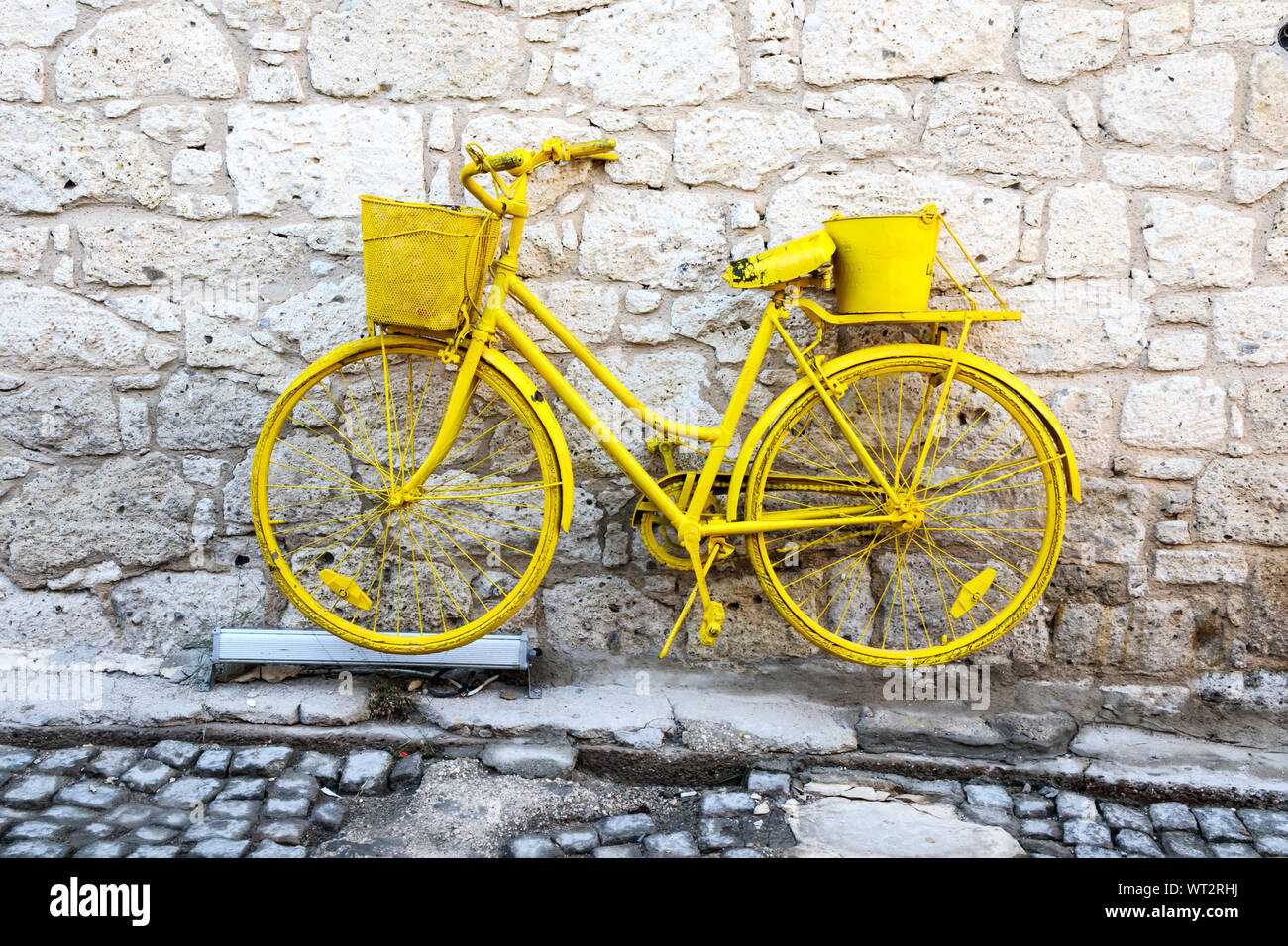 Gelbe Fahrrad gegen eine Mauer aus Stein in Alacati, Izmir, Türkei Stockfoto