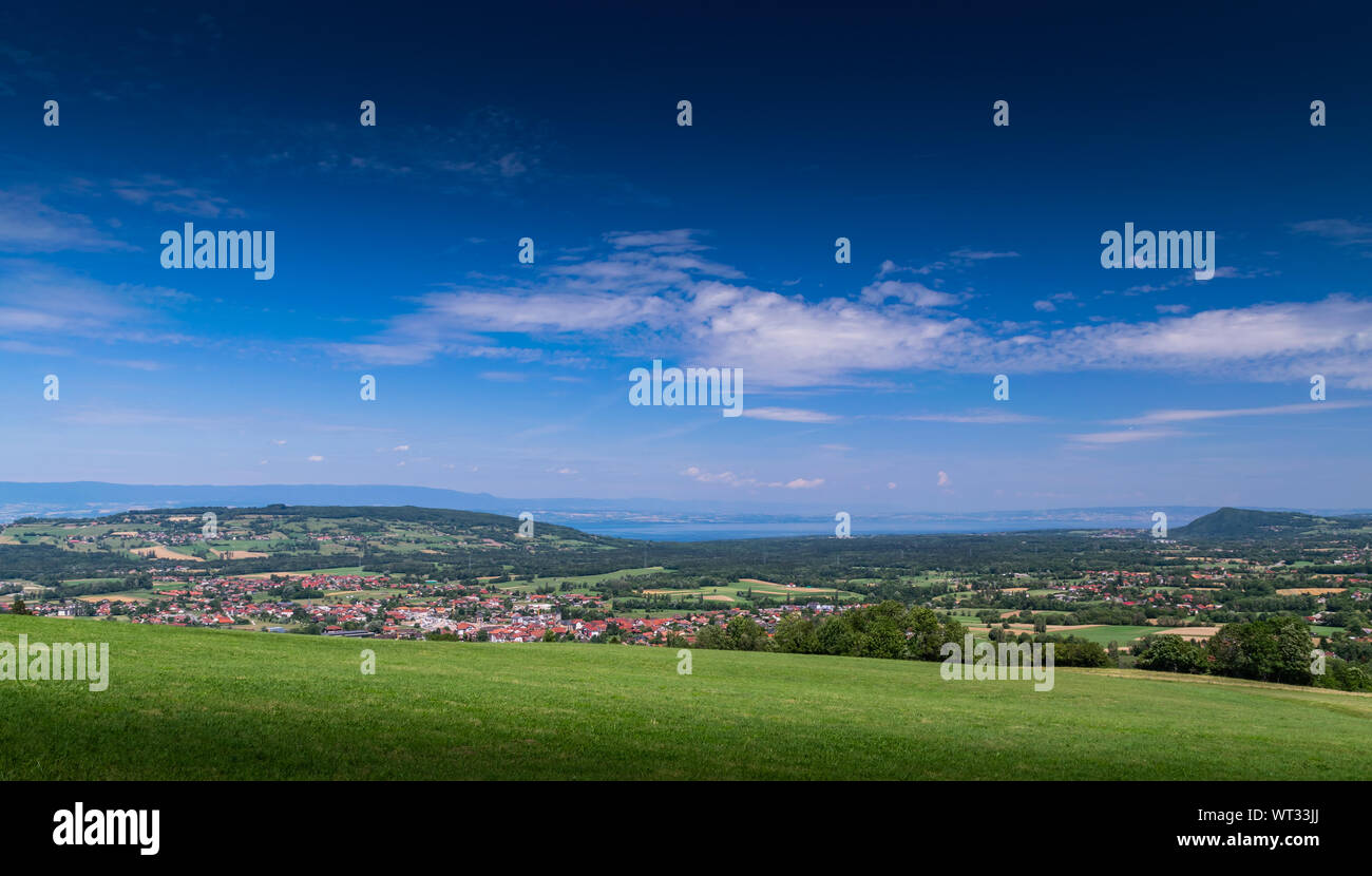 Stadt Landschaft in die Berge, Hügel, Felder, Wälder, grüne Wiesen, Seen in der Ferne und blauer Himmel mit Wolken. Stadt Bons-en-Chablais in Frankreich. Stockfoto