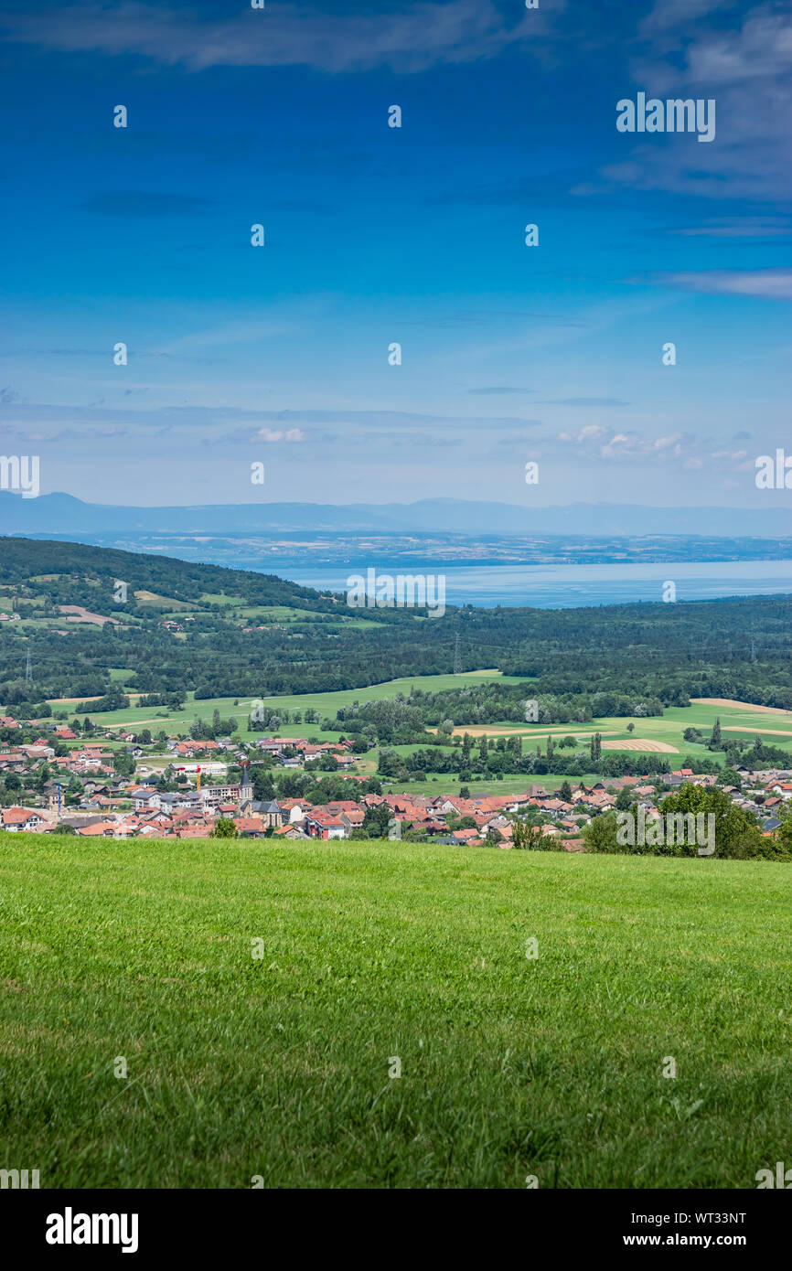 Stadt Landschaft in die Berge, Hügel, Felder, Wälder, grüne Wiesen, Seen in der Ferne und blauer Himmel mit Wolken. Stadt Bons-en-Chablais in Frankreich. Stockfoto