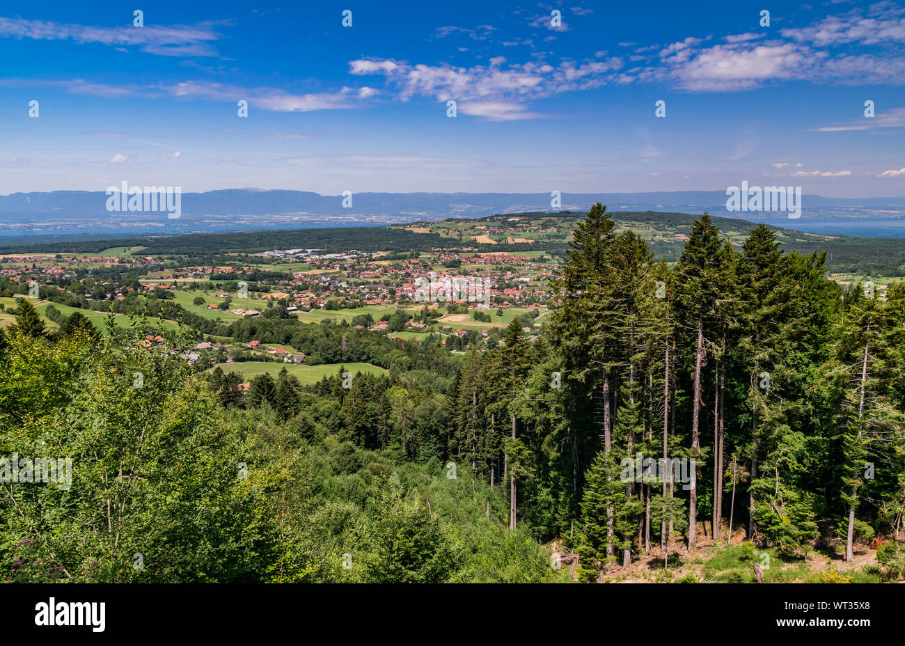 Stadt Landschaft in die Berge, Hügel, Felder, Wälder, grüne Wiesen, Seen in der Ferne und blauer Himmel mit Wolken. Stadt Bons-en-Chablais in Frankreich. Stockfoto