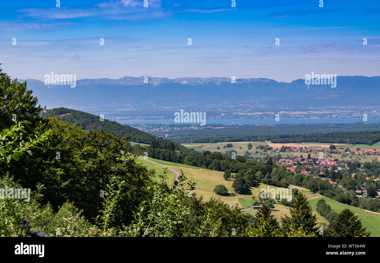 Stadt Landschaft in die Berge, Hügel, Felder, Wälder, grüne Wiesen, Seen in der Ferne und blauer Himmel mit Wolken. Stadt Bons-en-Chablais in Frankreich. Stockfoto