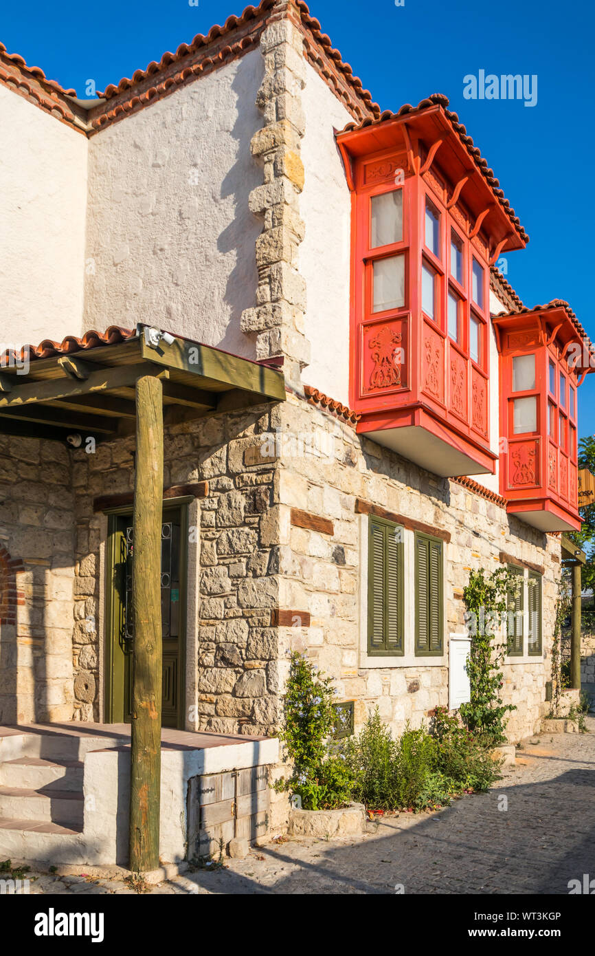 Alacati, Türkei - 3. September 2019: Haus mit roten Balkon Windows. Die Stadt ist ein beliebtes Ziel für Touristen. Stockfoto