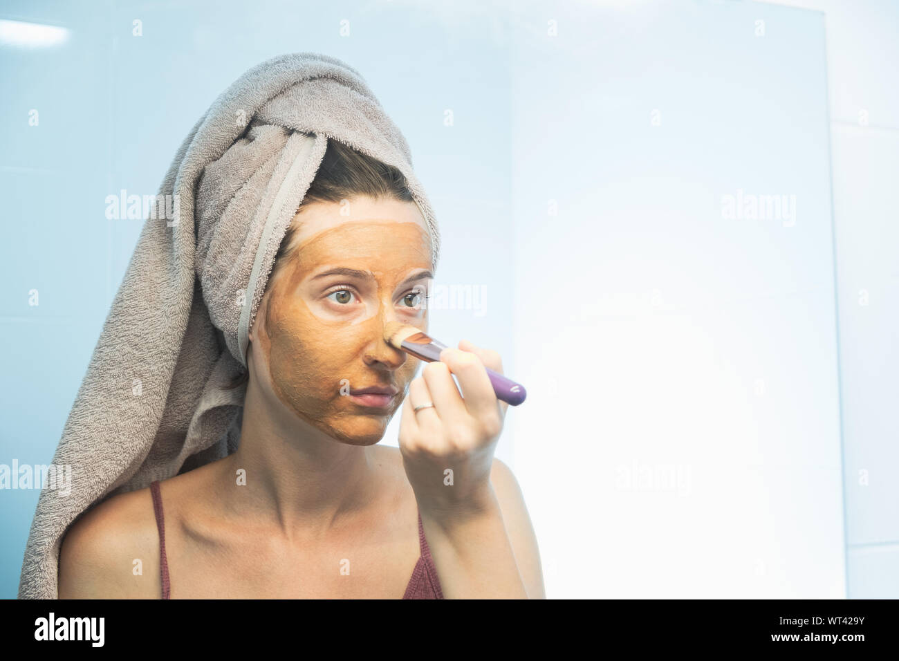 Eine junge Frau setzt eine Clay Mask auf Ihrem Gesicht mit einer Bürste. Das Konzept der Selbsthilfefunktion, richtige Gesichtspflege, Hautpflege Routine Stockfoto