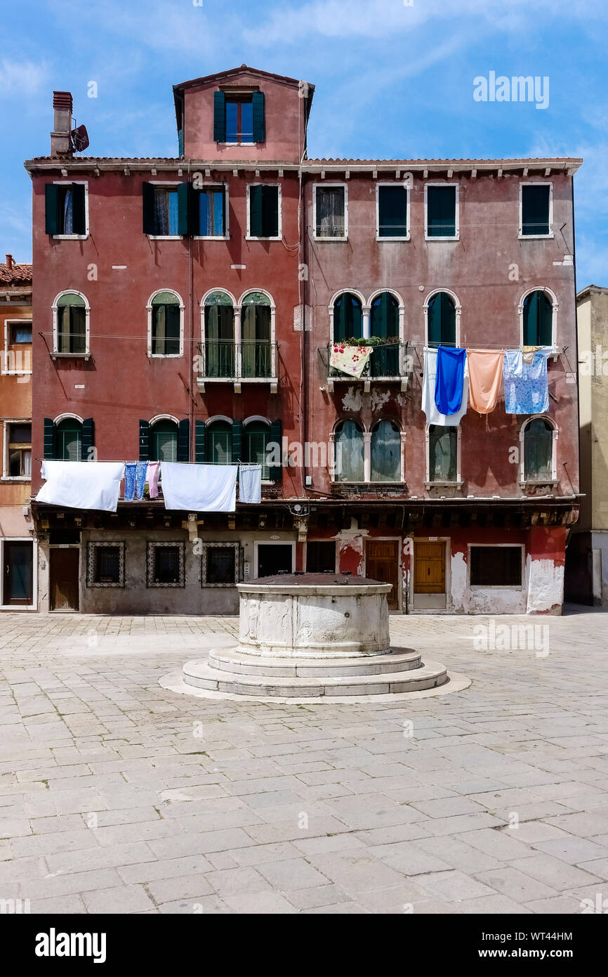 Alte typisch venezianische Gebäudefassade mit Wäscheleine mit Kleidung in einem kleinen venezianischen Platz, Venedig, Venetien, Italien. Europa, EU. Stockfoto