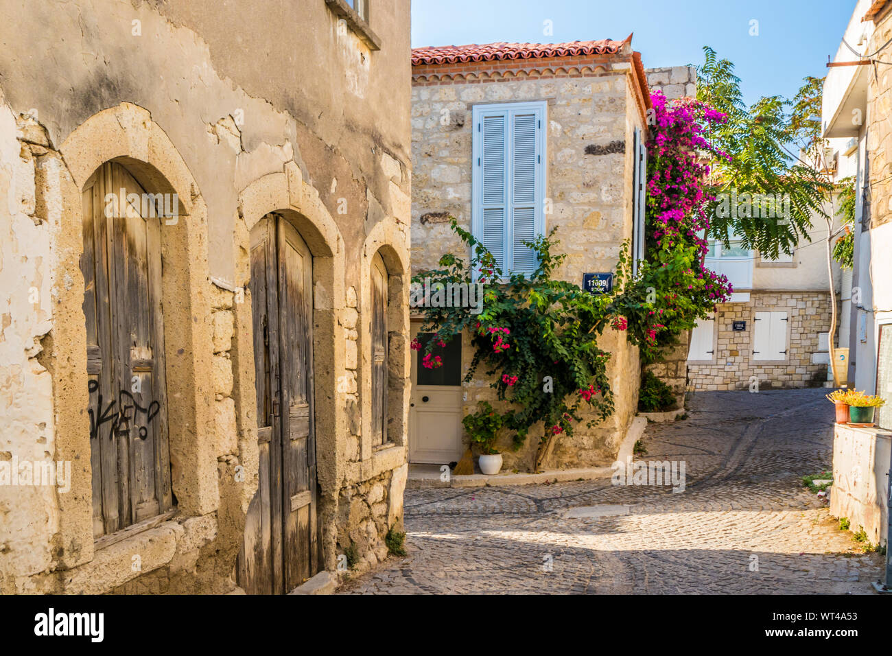 Alacati, Türkei - 3. September 2019: Straße mit Kopfsteinpflaster und alten Häusern aus Stein. Die Stadt ist ein beliebtes Ziel für Touristen. Stockfoto