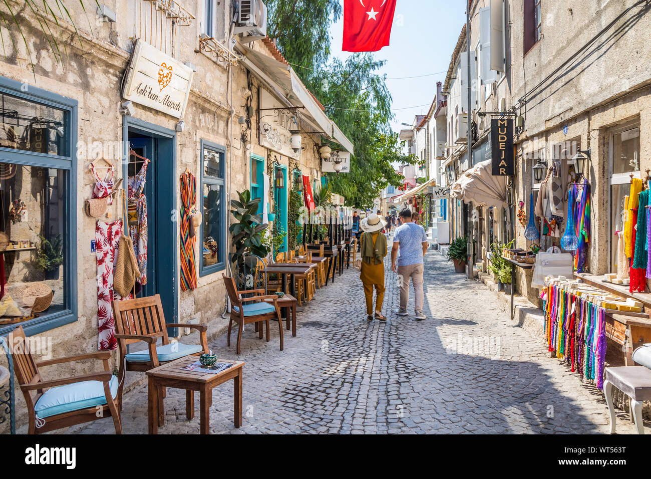 Alacati, Türkei - 4. September 2019: Paar hinunter eine schmale Straße mit Geschäften. Die Stadt ist ein beliebtes Ziel für Touristen Stockfoto