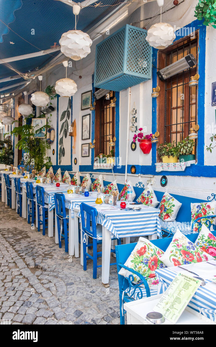 Alacati, Türkei - 5 September 2019: Blau und Weiß Restaurant in engen Straße. Die Stadt ist ein beliebtes Ziel für Touristen. Stockfoto