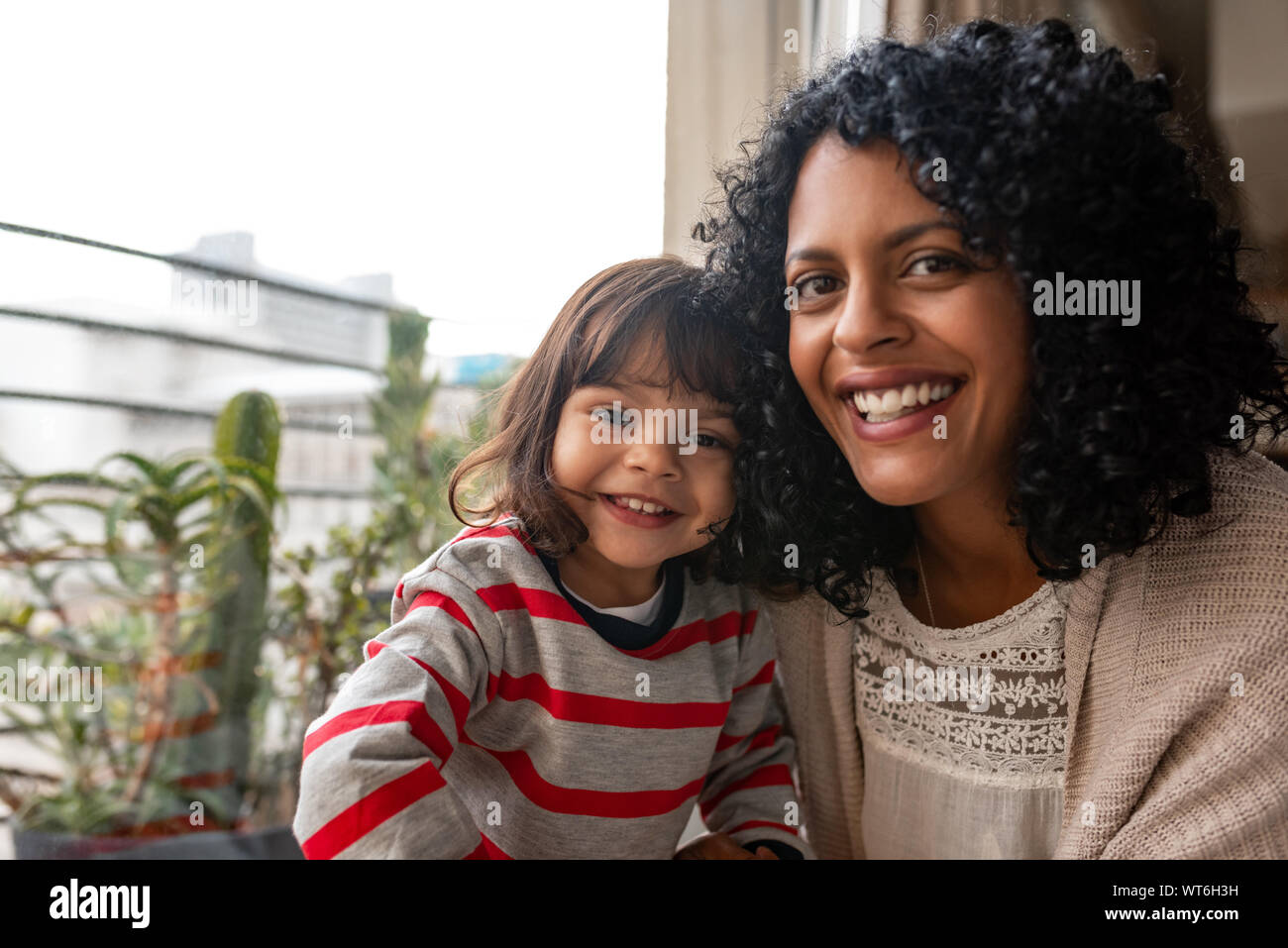 Lächelnde Mutter und ihre süße Tochter zusammen zu Hause sitzen Stockfoto