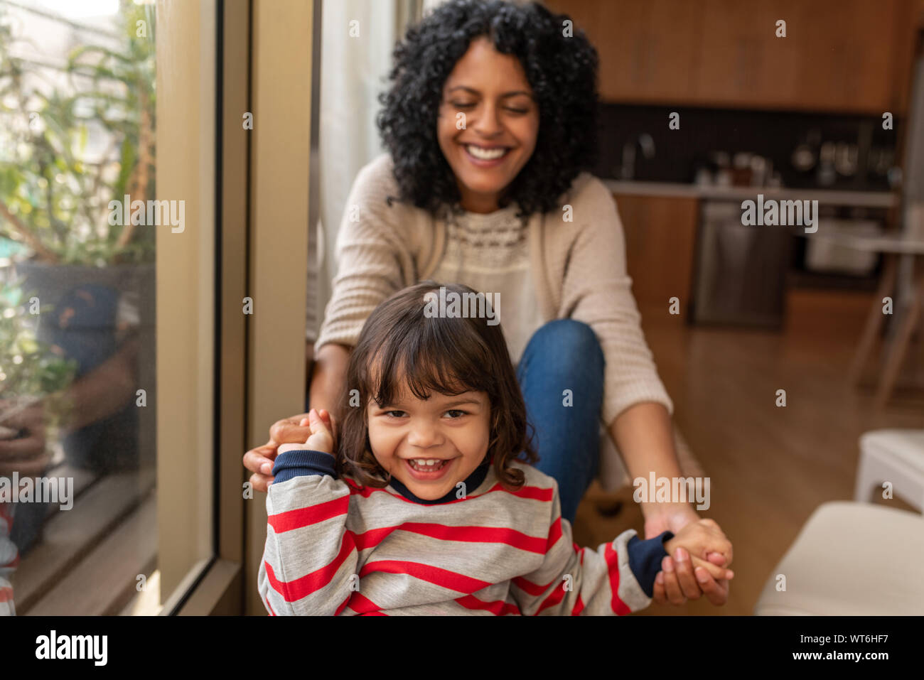 Lächelnde Mädchen und ihre Mutter zusammen zu Hause sitzen Stockfoto