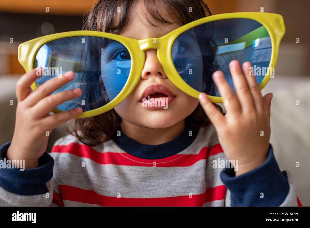 Adorable kleine Mädchen spielen mit übergroßen Neuheit Sonnenbrille zu Hause Stockfoto