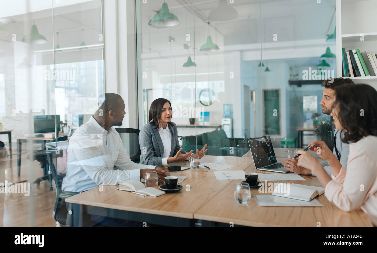 Vielfältige Gruppe von Geschäftsleuten sprechen gemeinsam innerhalb eines Büros Stockfoto
