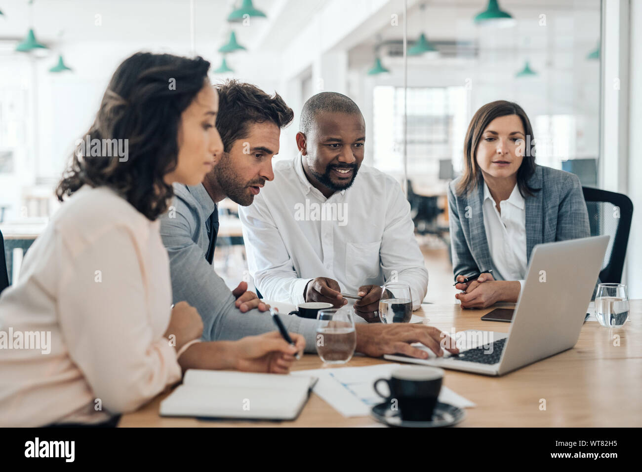 Diverse Geschäftsleute Lächeln beim zusammen, die an einem Notebook arbeitet Stockfoto