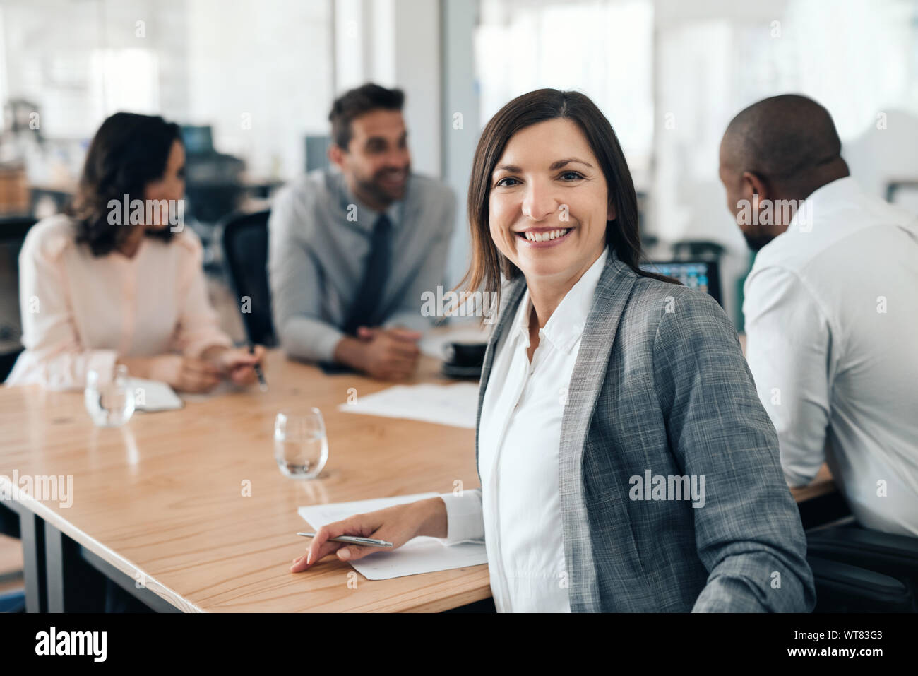 Lächeln, Geschäftsfrau, Sitzen mit Kollegen während einer Konferenz Stockfoto