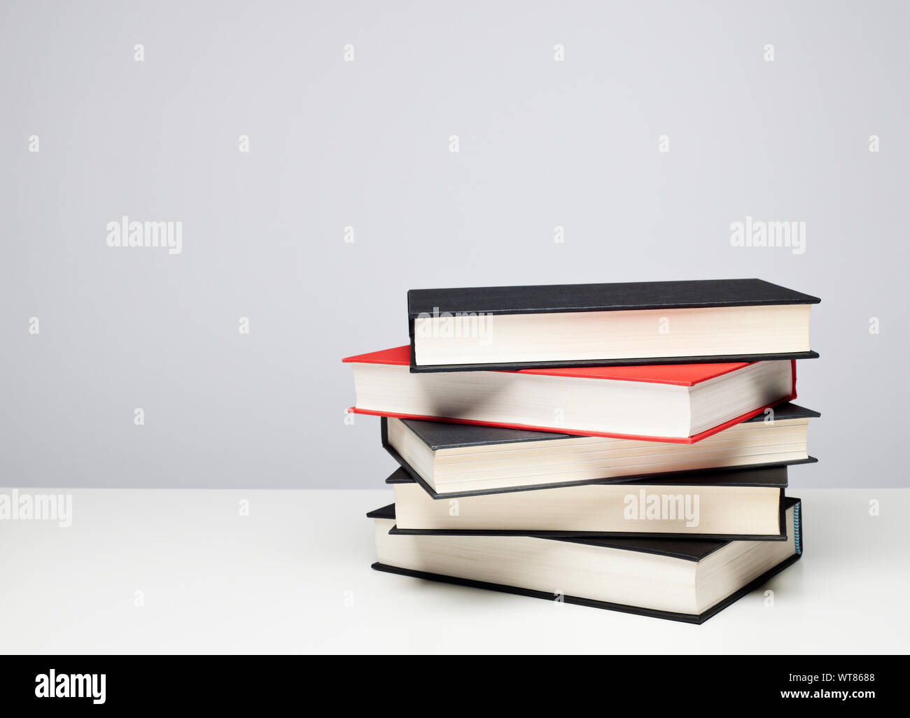 Stapel von vier schwarze und eine rote gebundene Bücher auf einem Tisch Stockfoto