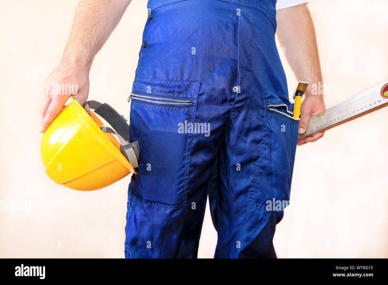 Bauarbeiter auf der Baustelle mit schützenden einheitliche, Bau Service Werkzeuge und Ausrüstung, Overall und hält gelben Helm, Hammer. Stockfoto