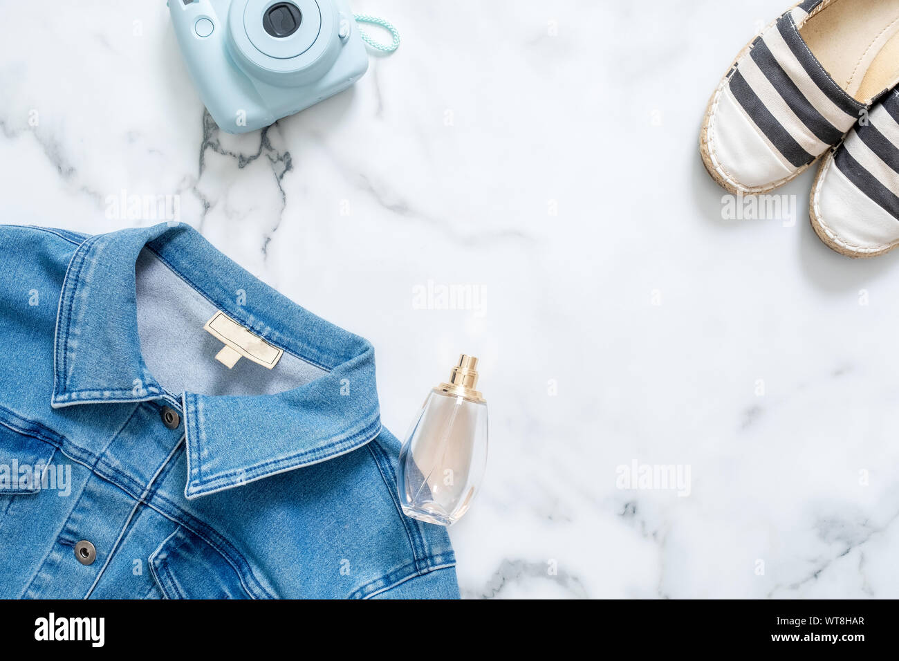 Schönheit blogger Schreibtisch mit feminine Jeans Jacke, hipster instant Foto Kamera, duftende Flasche Parfüm, topmodische Sandalen. Der sportliche Frauen Stockfoto