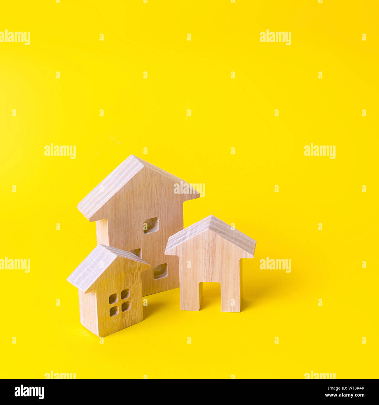 Drei Häuser auf einem gelben Hintergrund. Kauf und Verkauf von Immobilien, Bau. Wohnungen und Wohngebäude in einer Stadt oder Siedlung. In Stockfoto