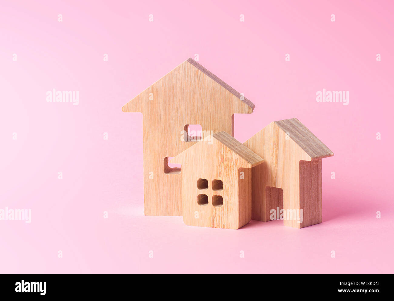Drei Häuser auf einem rosa Hintergrund. Kauf und Verkauf von Immobilien, Bau. Wohnungen und Wohngebäude in einer Stadt oder Siedlung. Inve Stockfoto