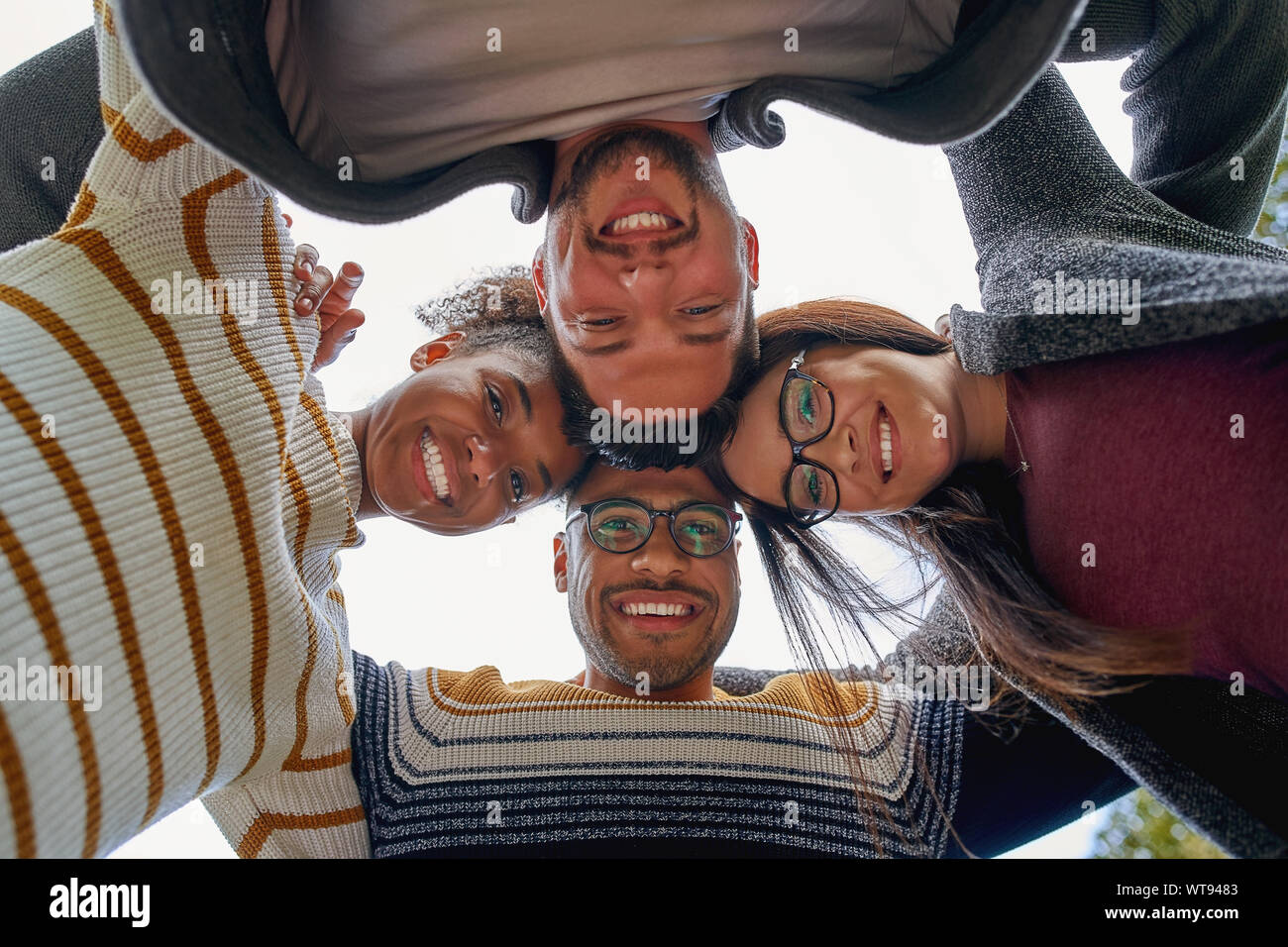 Low Angle View von Happy freundlich vielfältigen, multi-ethnischen Freunde bilden einen Kreis und in die Kamera lächeln - Teamarbeit Stockfoto