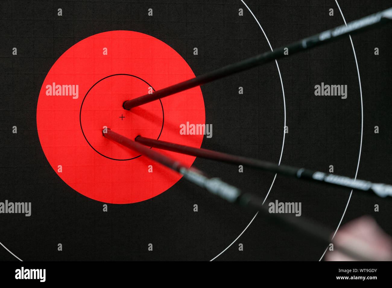 Drei Pfeile in der Mitte der schwarzen und roten Bogenschießen Ziel. Genauigkeit und Präzision. Stockfoto