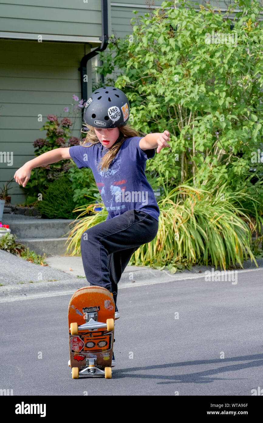 Die jungen langhaarigen Jungen skateboarding auf die Wohnstraße. Stockfoto