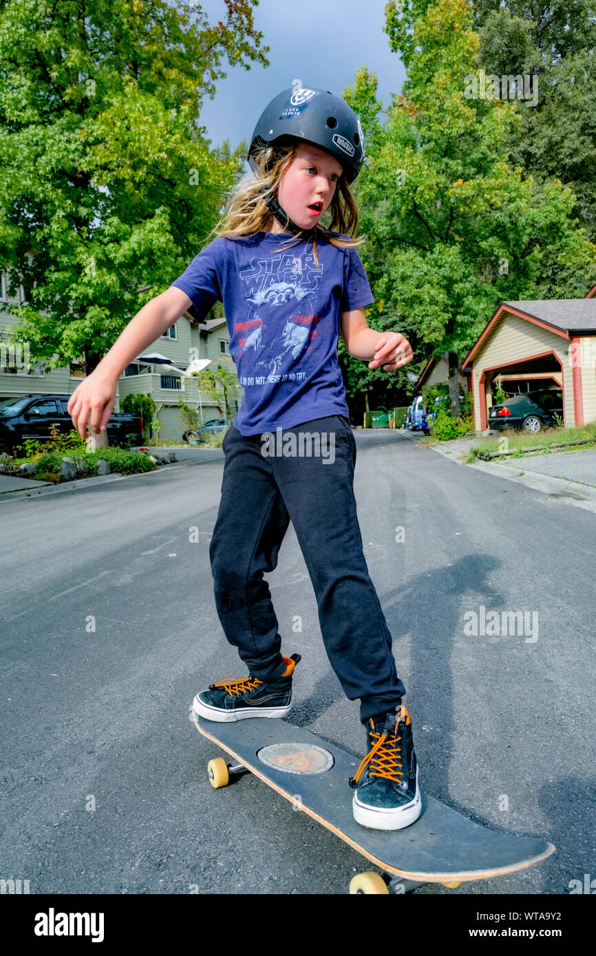 Die jungen langhaarigen Jungen skateboarding auf die Wohnstraße. Stockfoto