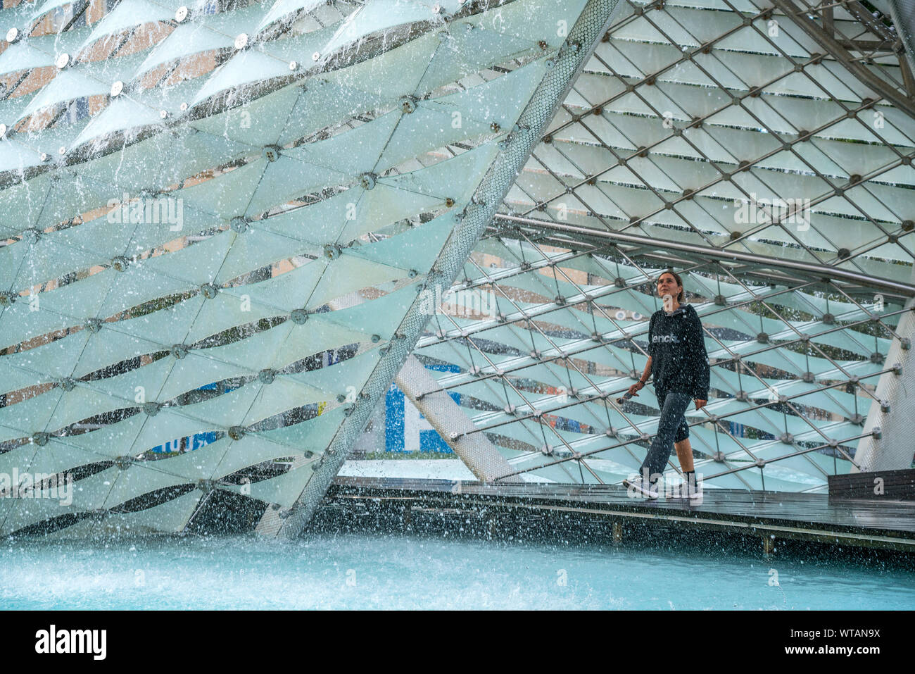 Touristin läuft durch den Brunnen der Freiheit, Posen, Polen, Europa | Wandern im inneren Freiheit Brunnen am Plac Wolnooeci Poznan, Polen, Euro Stockfoto