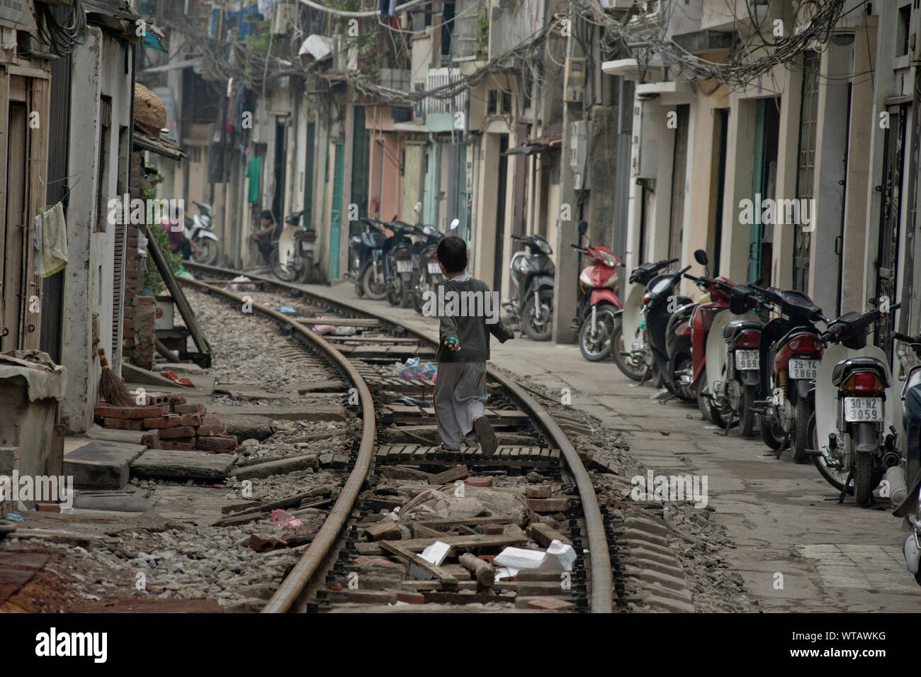 Junge läuft auf der Bahnlinie durch die Slums von Hanoi Stockfoto