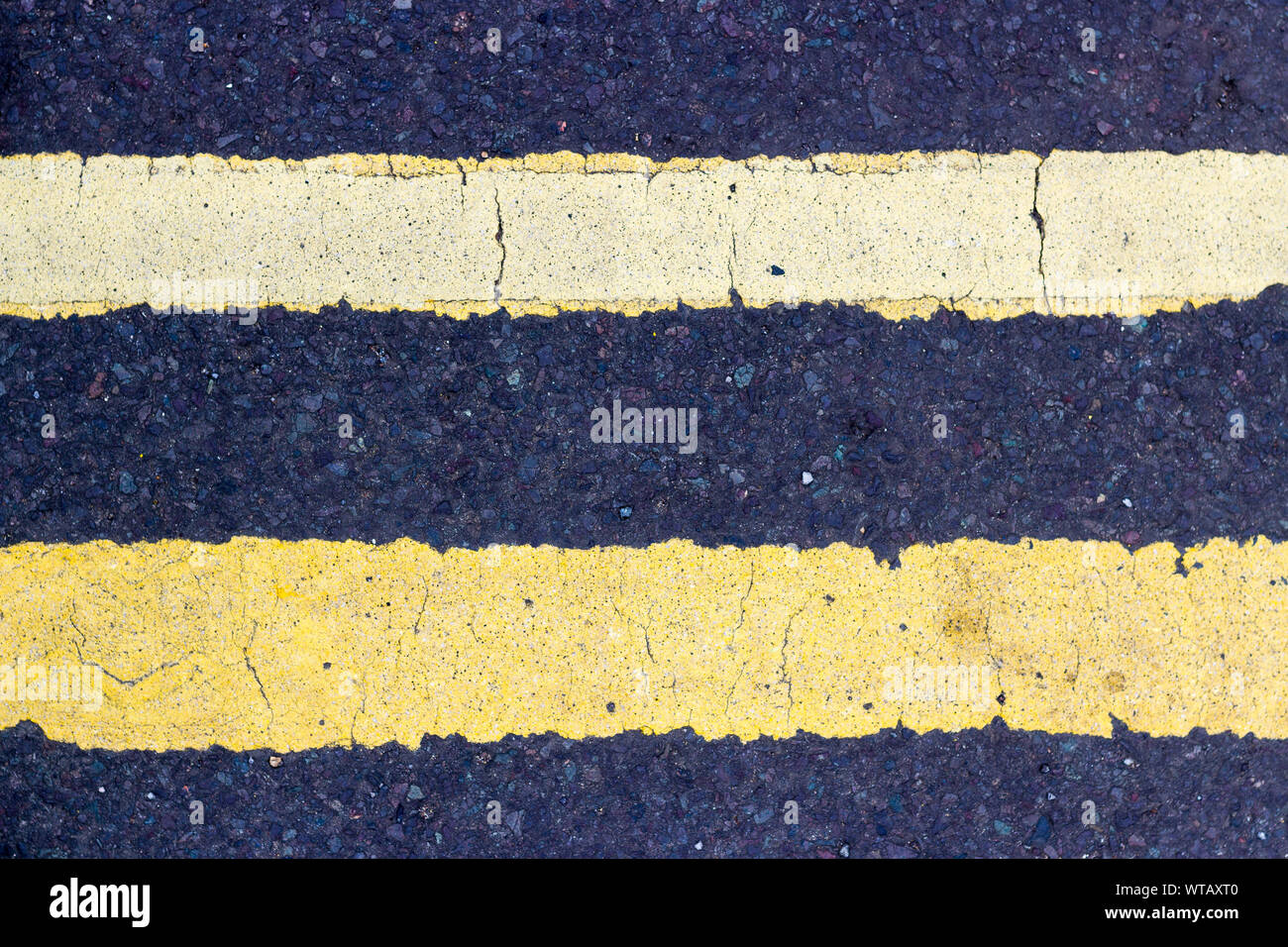 Zwei parallele gelbe Fahrbahnmarkierung Linien horizontal auf dem schwarzen Asphalt Stockfoto