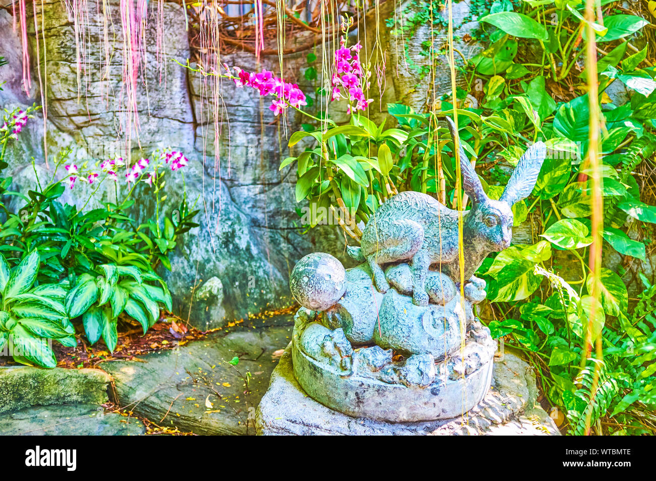 Der kleine Stein Skulptur des Kaninchens unter dem Grün des Wat Saket Tempel's Garten, Bangkok, Thailand Stockfoto