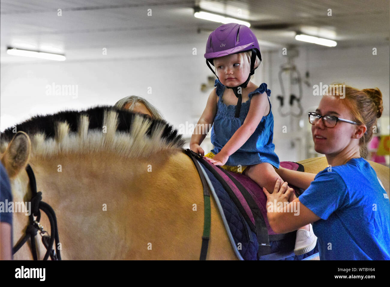 Reittherapie für behinderte Kinder und Erwachsene. Freiwillige helfen mit helfenden Patienten Mut und mit Pferden als Stütze Hoffnung gewinnen. Stockfoto