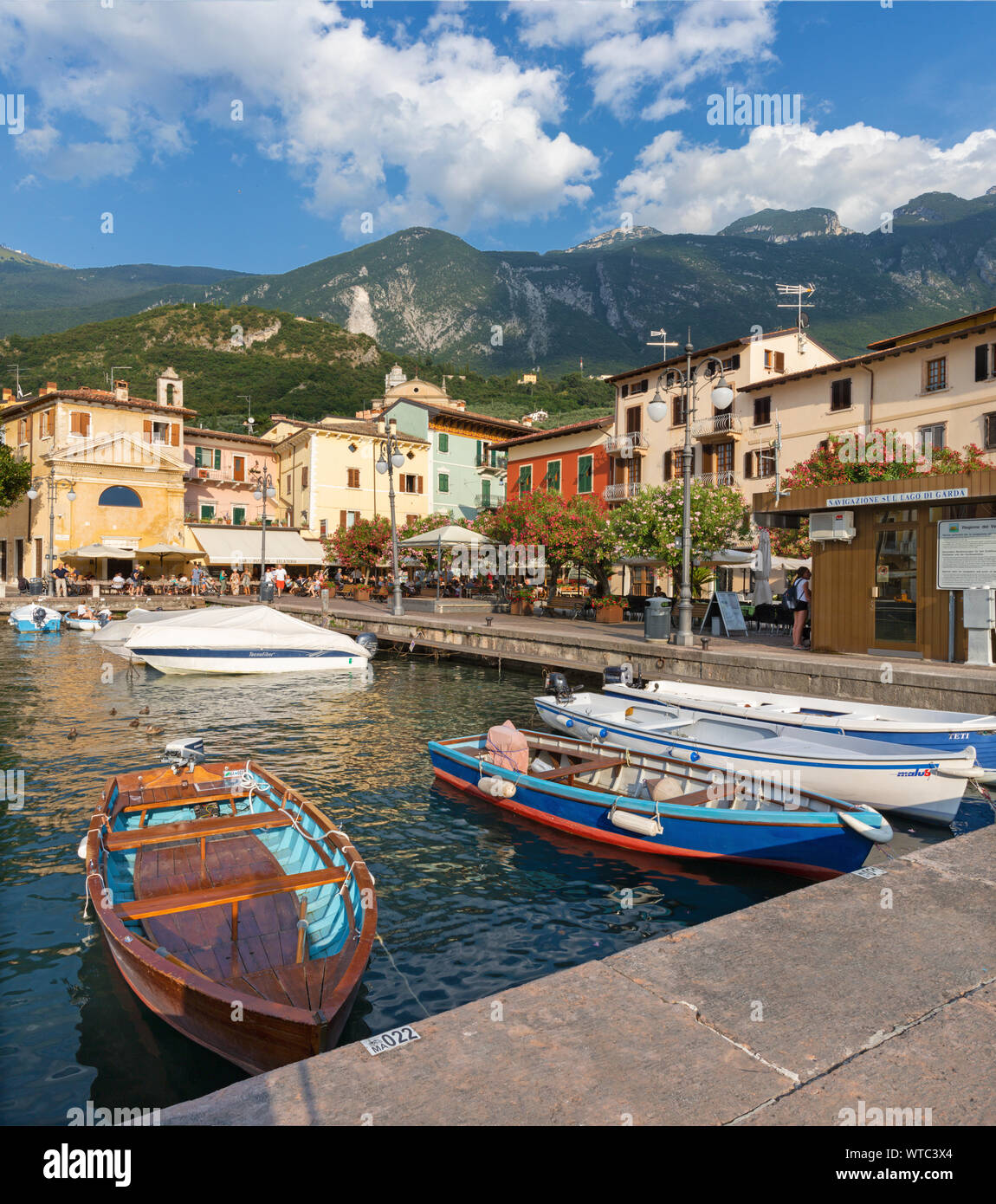 MALCESINE, Italien, 13. Juni 2019: Der kleine Hafen am Ufer des Lago di Garda See mit dem 2000 m hohen Bergen im Hintergrund. Stockfoto