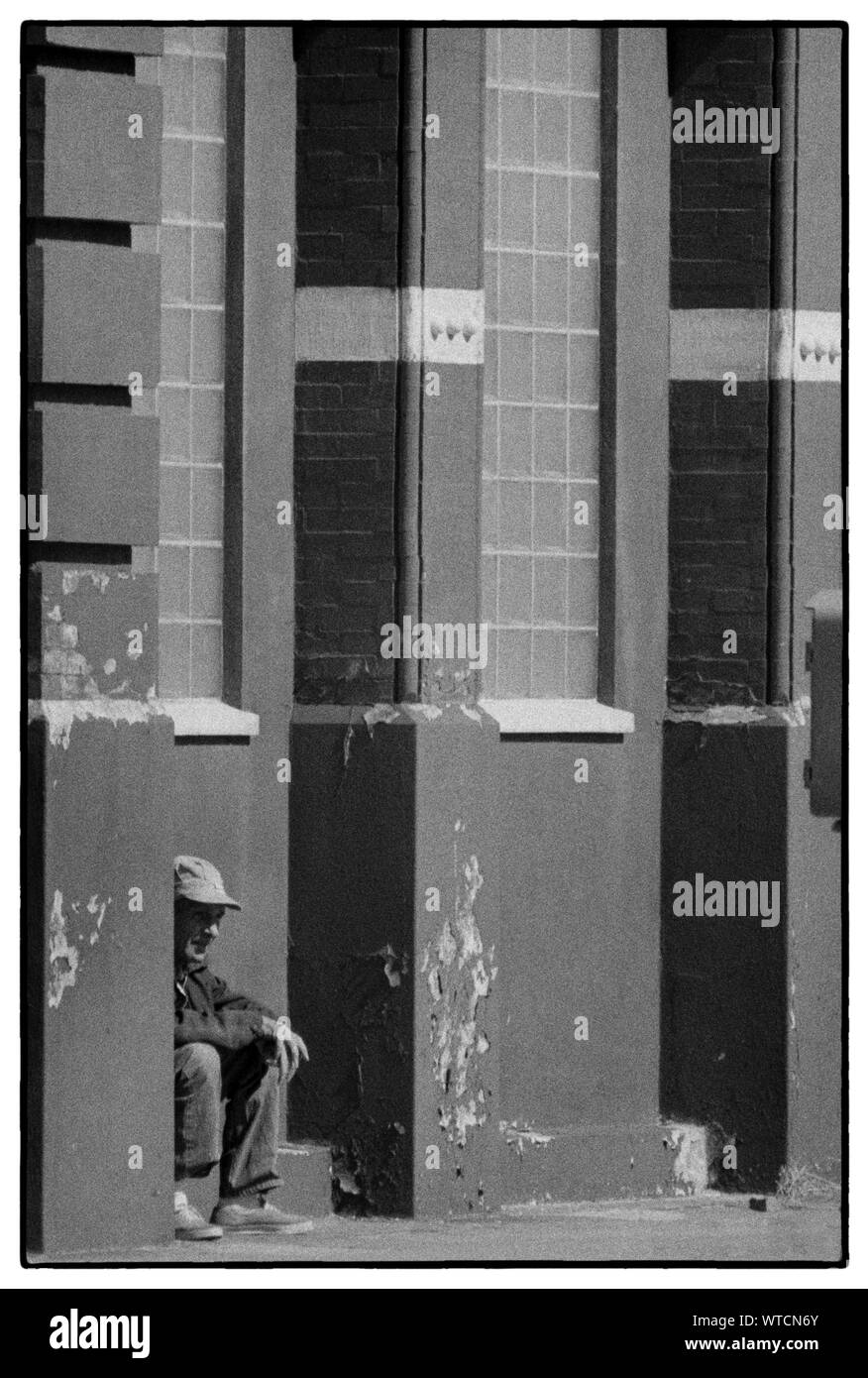 Aus Arbeit heraus. Ein Mann sitzt vor einem Galveston Gebäude während eines Longshoreman Streik. Stockfoto