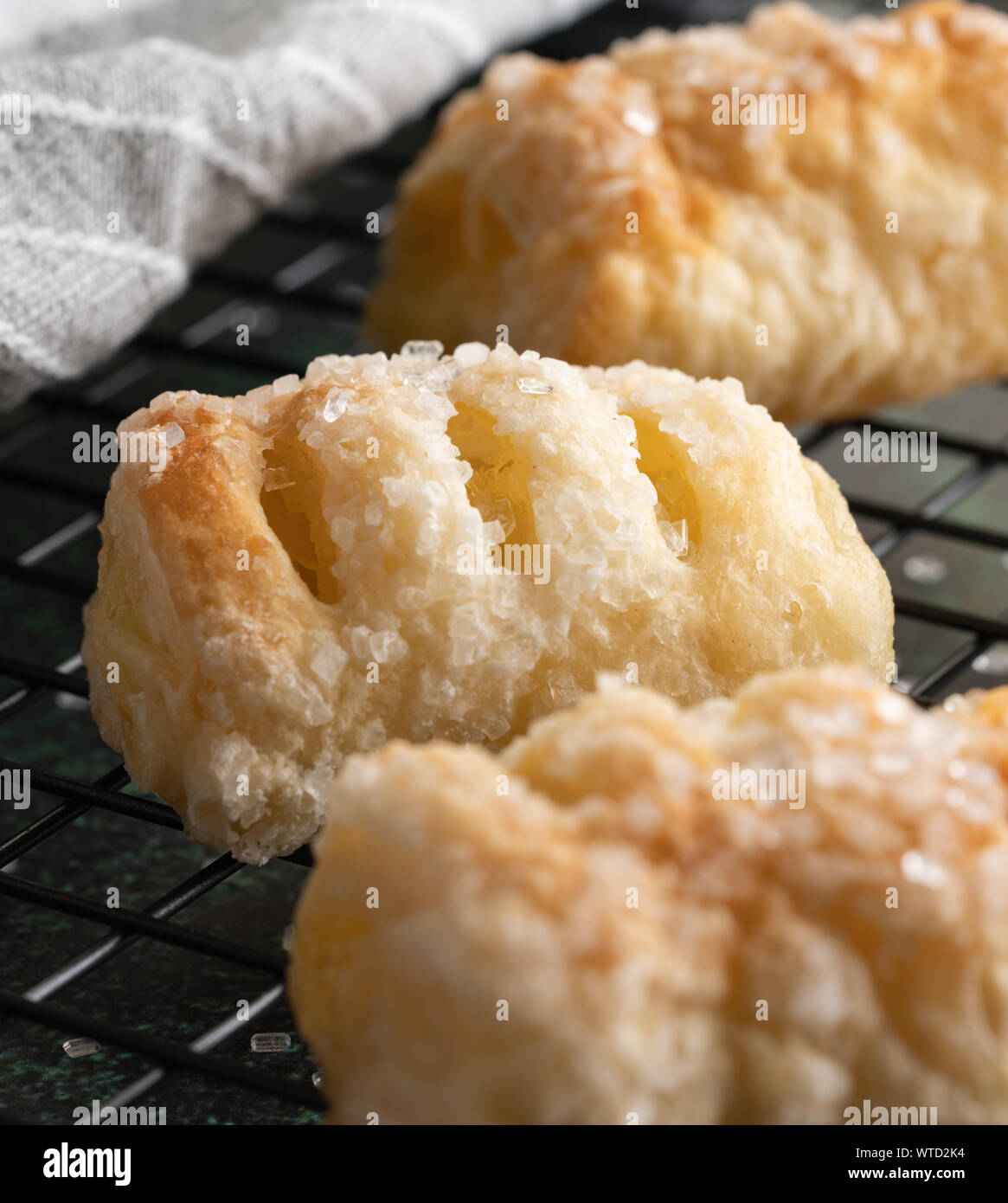 Zitrone Blätterteig gefüllt mit großen Kristallen von grobem Zucker auf einem schwarzen Backaufsatz in selektiven Fokus Nahaufnahme Stockfoto