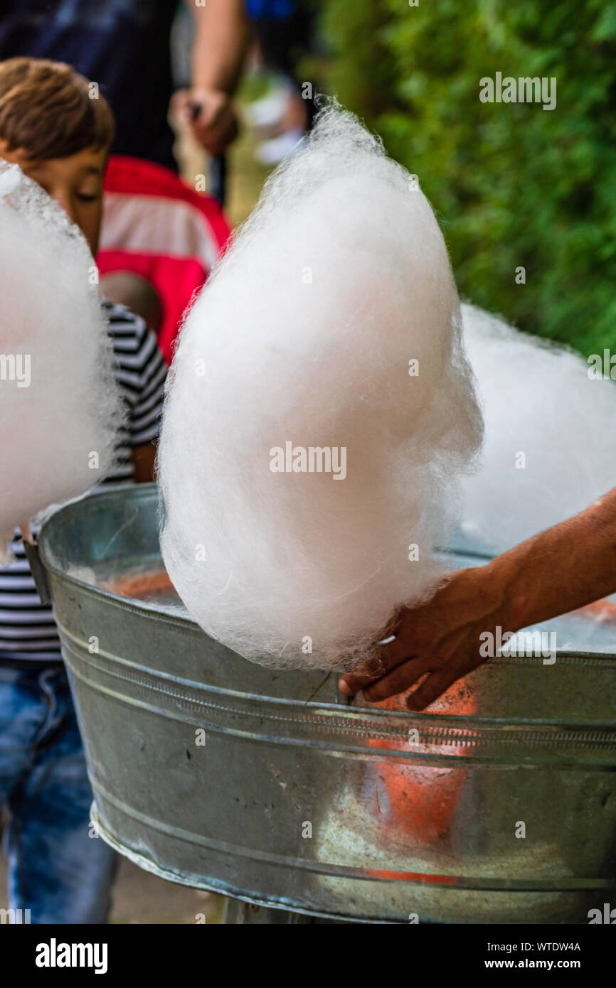 Junger Mann herstellen und verkaufen von Zuckerwatte auf eine Gasse im Park auf einem Festival in Bukarest, Rumänien, 2019 Stockfoto
