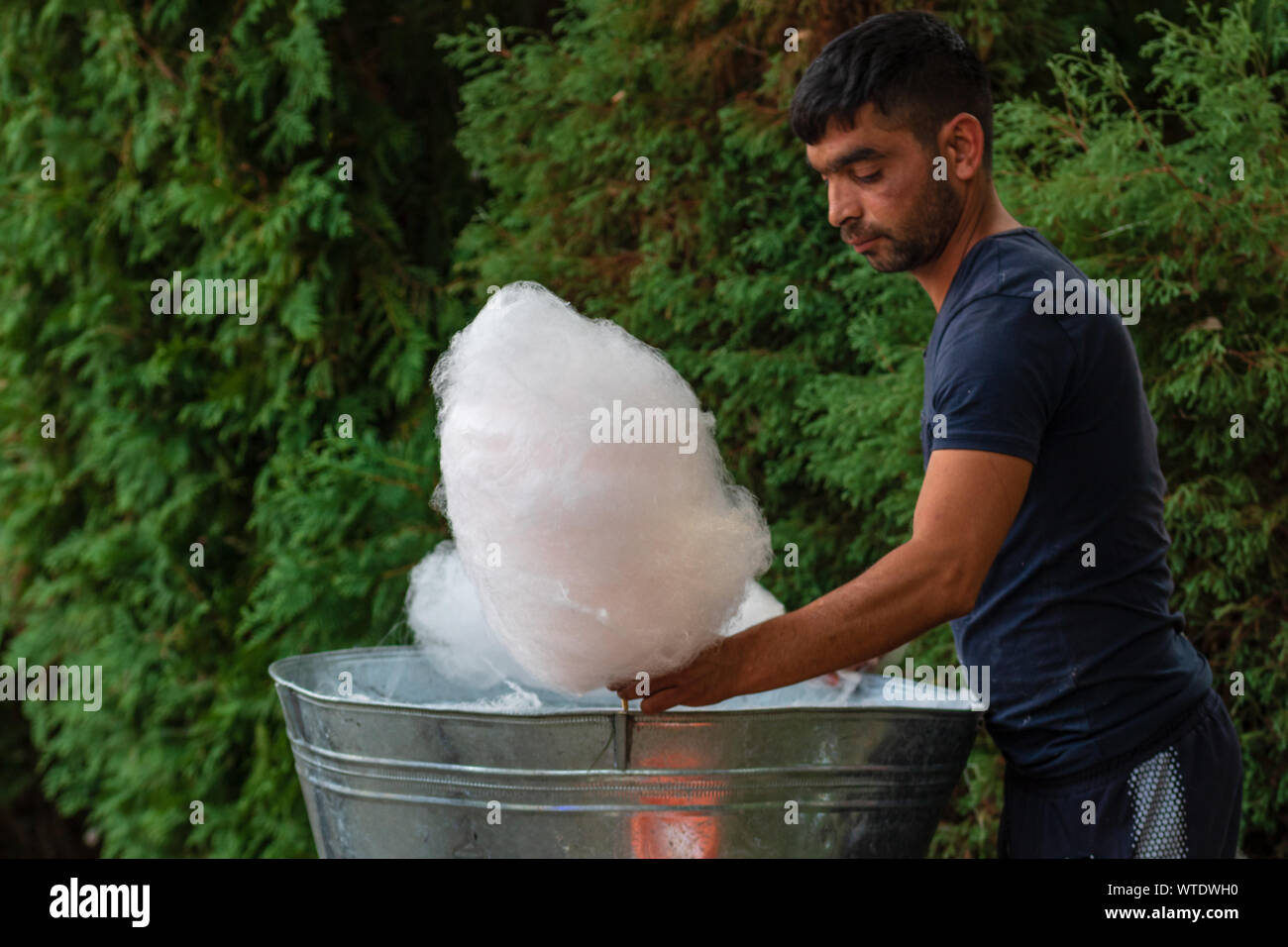 Junger Mann herstellen und verkaufen von Zuckerwatte auf eine Gasse im Park auf einem Festival in Bukarest, Rumänien, 2019 Stockfoto