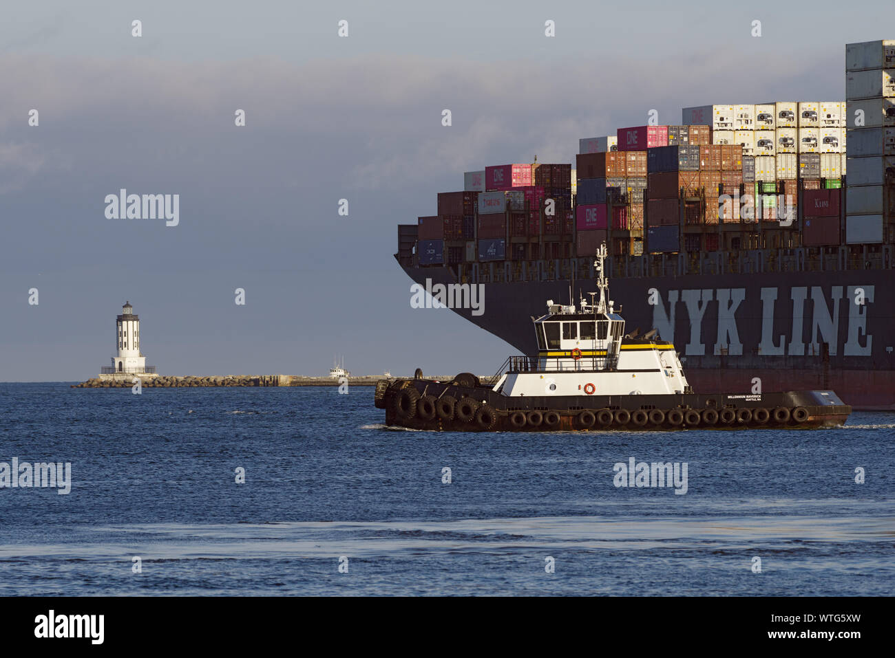 NYK Line Containerschiff mit Abfahrt vom Hafen von Los Angeles sowie Schlepper und Angeles Harbor Light. Stockfoto