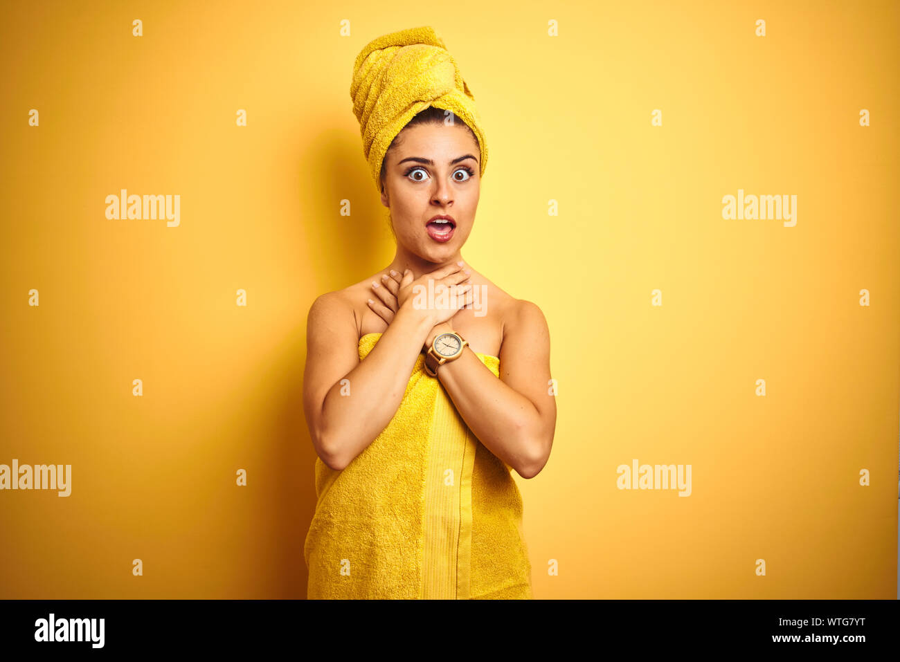 Junge schöne Frau mit Handtuch nach der Dusche über isolierte gelben Hintergrund schreien und Ersticken, weil schmerzhaft ersticken. Gesundheitliches Problem. Lens Stockfoto