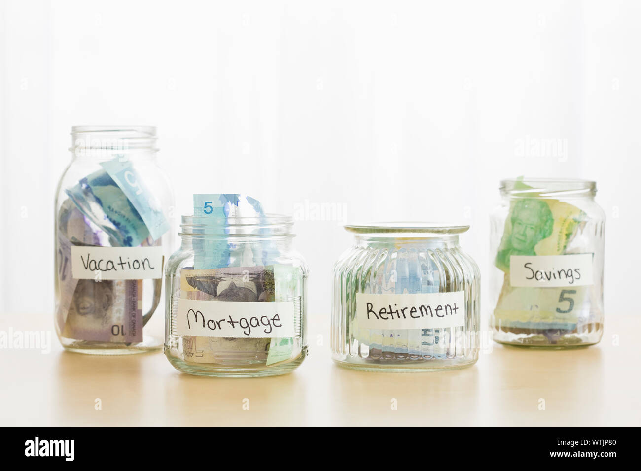 Gläser mit verschiedenen Etiketten mit Kanadischen Dollar gefüllt Stockfoto