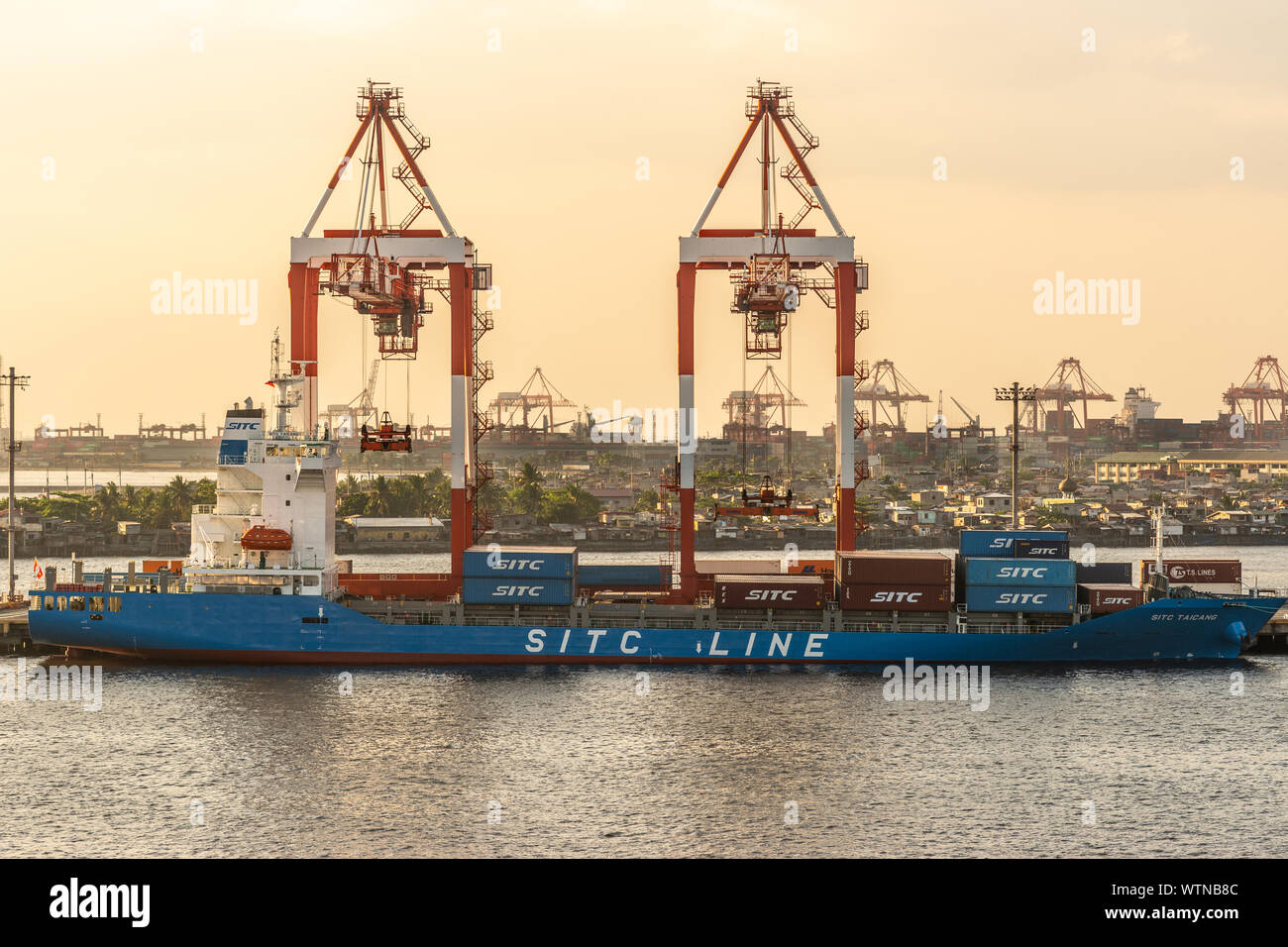 Manila, Philippinen - 5. März 2019: South Harbor Abenddämmerung. Gelbliche Himmel hinter dem Container Terminal, wo vorne die SITC Taichang Schiff Stockfoto