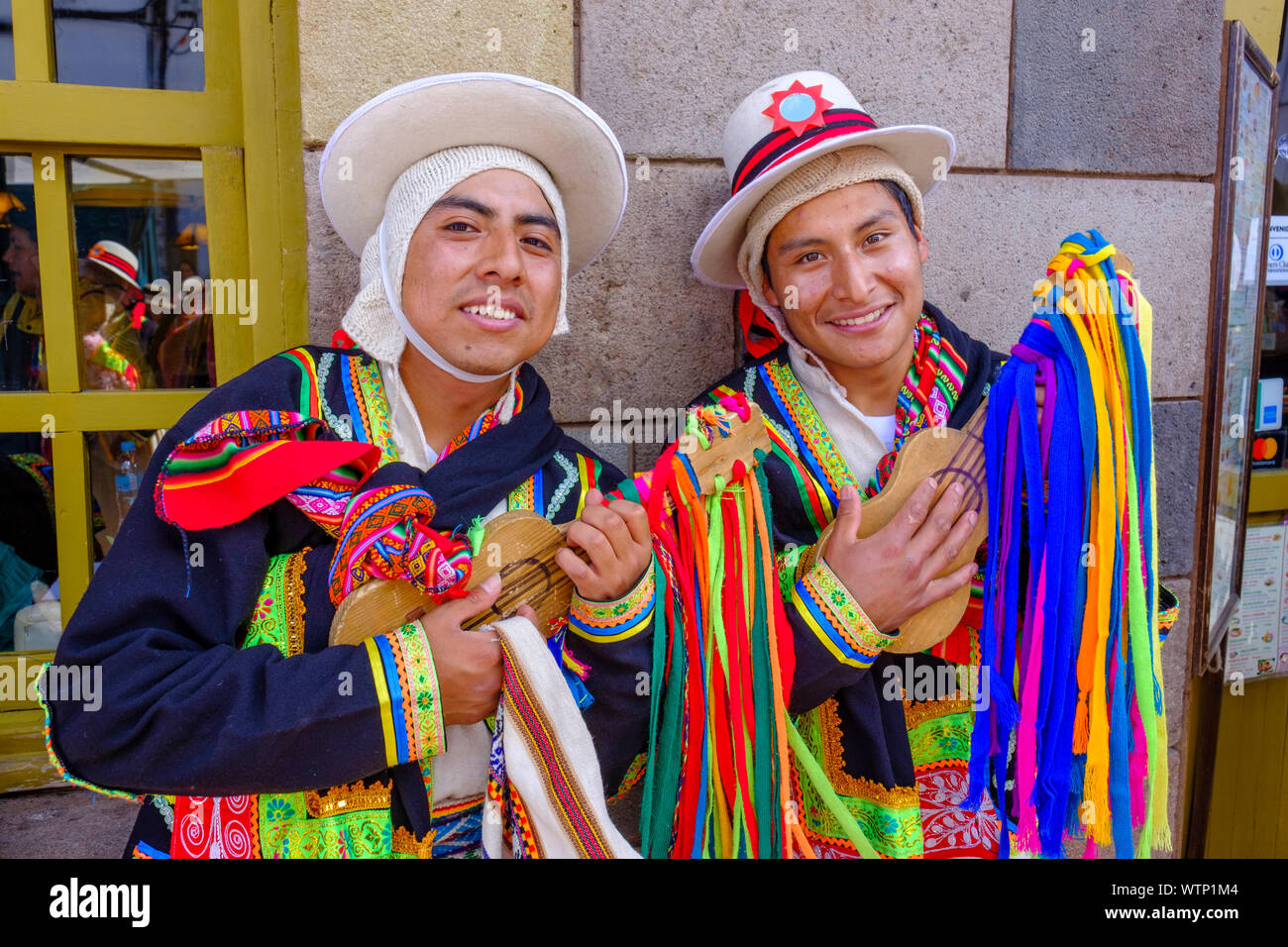 Porträt von zwei jungen Männern, Musiker holding Streichinstrumente, die traditionelle peruanische Kleidung und lächelnd, Cusco, Peru. Stockfoto