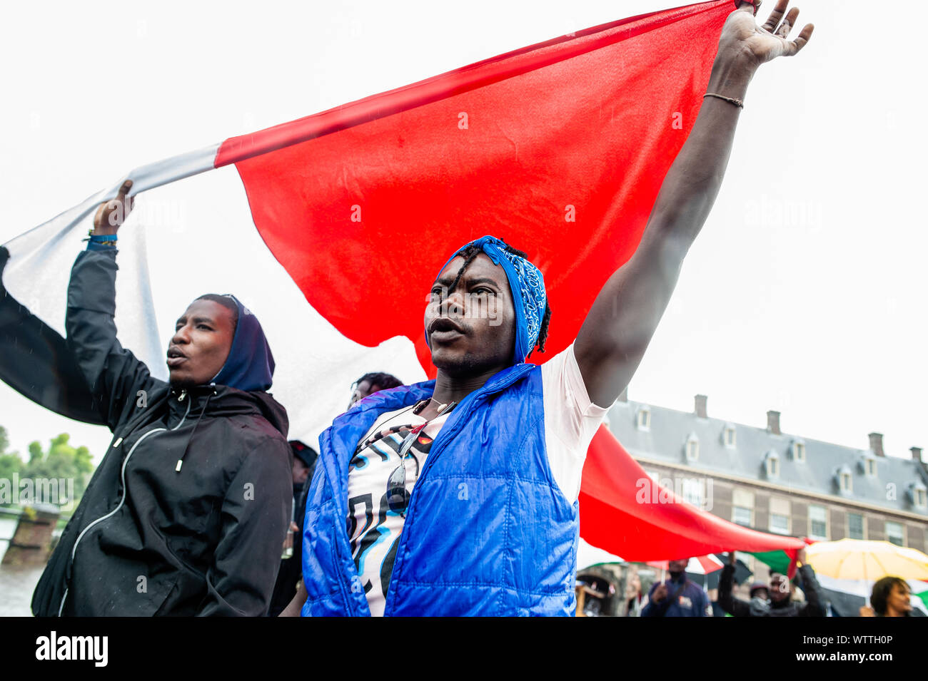 Eine Gruppe von sudanesischen Demonstranten halten eine große Sudanesische Fahne während der Demonstration vom 6. bis 11. September, einem internationalen Sudanesischen März fand in London starten und beenden in Den Haag Nach dem Stoppen in Frankreich und Belgien. Am 11. September, der März vor dem Internationalen Strafgerichtshof Gebäude angekommen, in Den Haag. Der März war in Solidarität mit der Sudanesischen Revolution statt und fordert die Verfolgung von militärischen Verbrecher im Sudan. Der März war von der sudanesischen Initiative Europa organisiert. Stockfoto