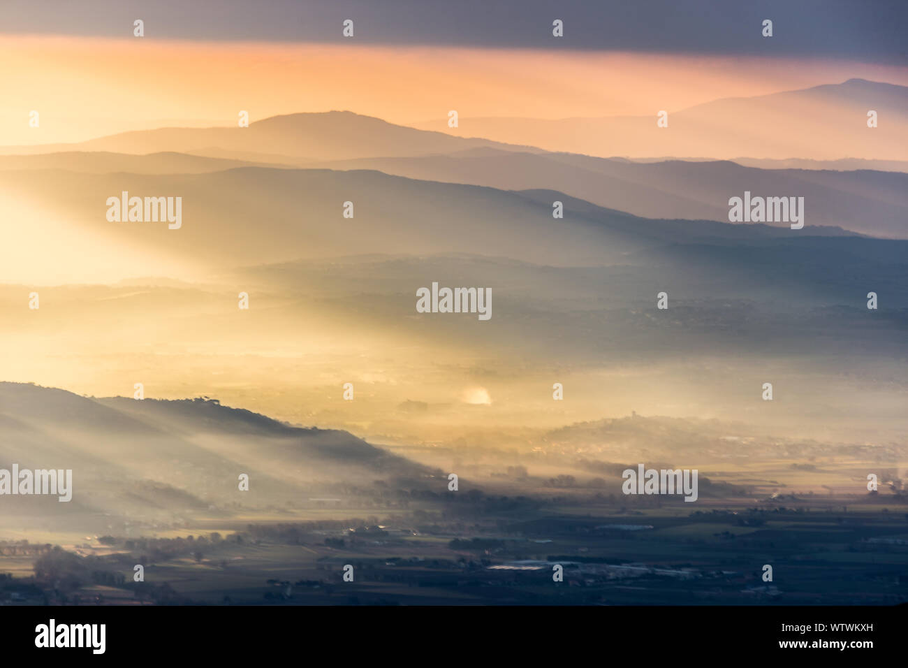 Sonnenstrahlen kommen über ein Tal in Umbrien (Italien) mit schönen goldenen Stunden Farben. Stockfoto