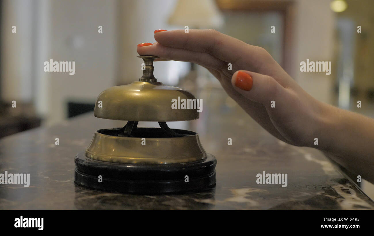 Die Hand eines jungen Mädchens mit einem Service Bell im Hotel Rezeption. Stockfoto