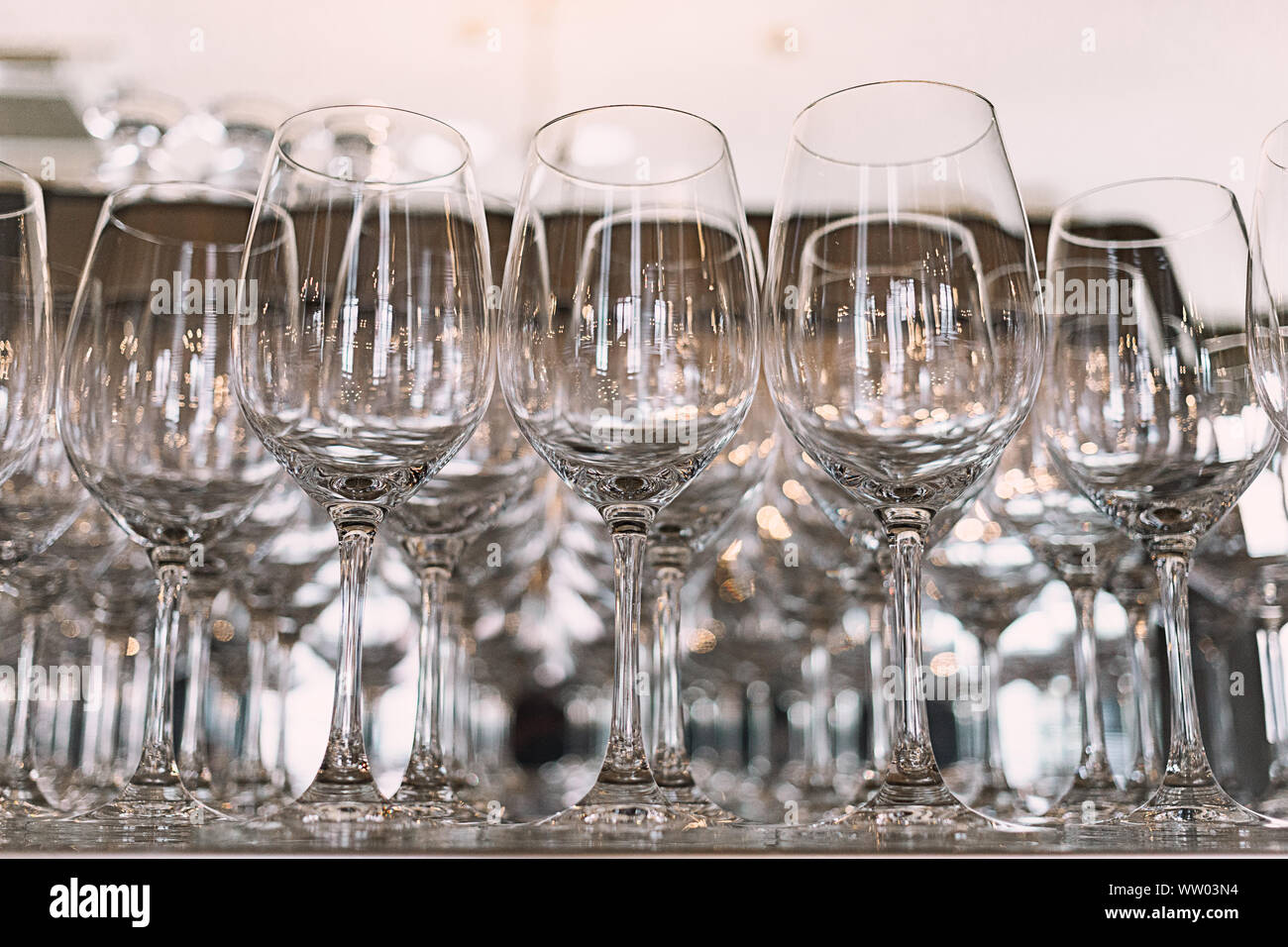 Viele Gläser auf einen Tisch. Leere Gläser in einer Reihe. Vielen leeren Likör Gläser. Viele leere Sektgläser hautnah. Glas Pokale auf dem weißen Stockfotografie