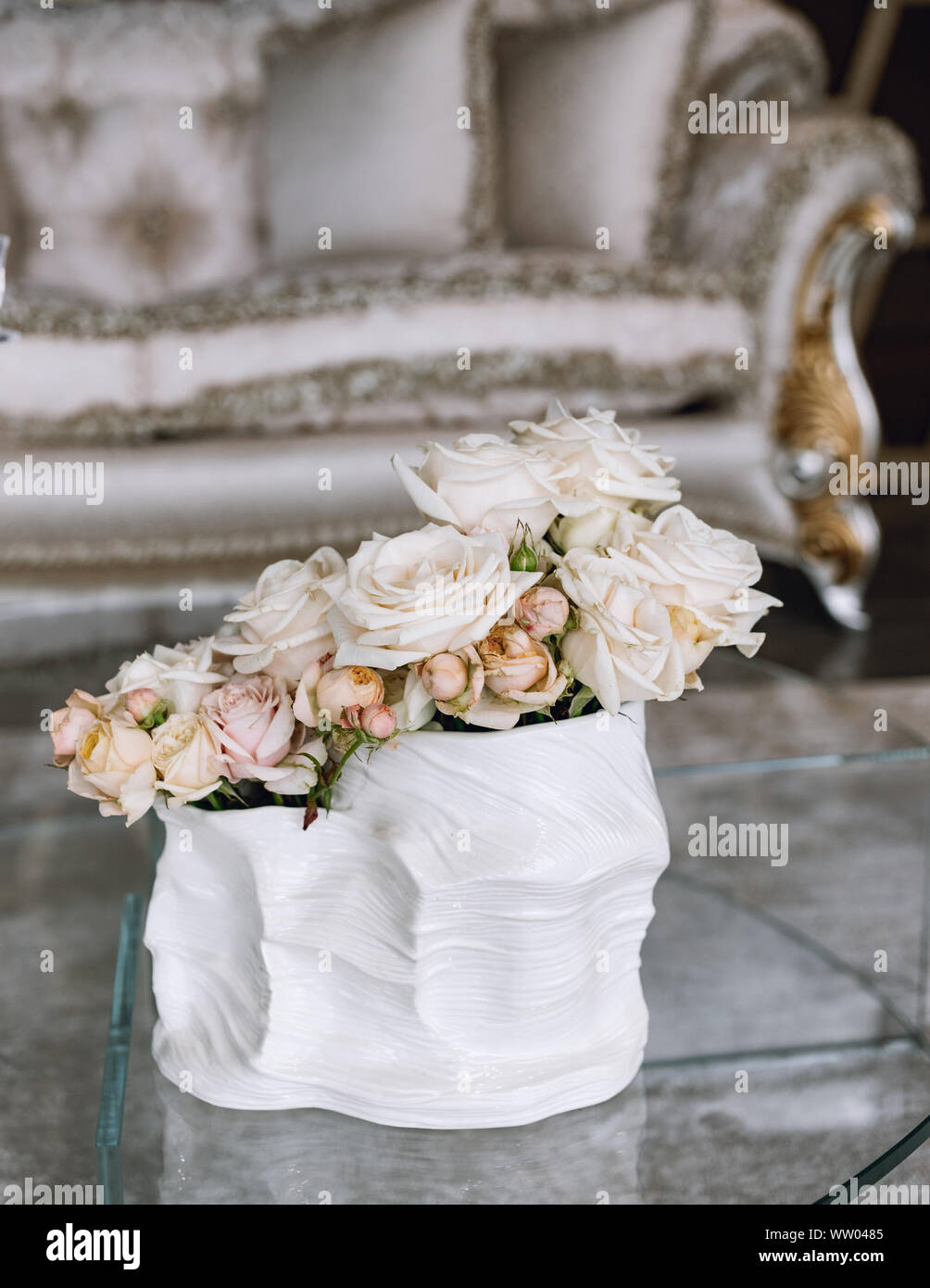 Blumenstrauß aus zarten rosa Rosen in einer Schale auf dem Tisch. Nachttisch, Innenraum eines Fashion House. Rokoko Sofa mit Vase rose. Luxus reiche Leben ro Stockfoto