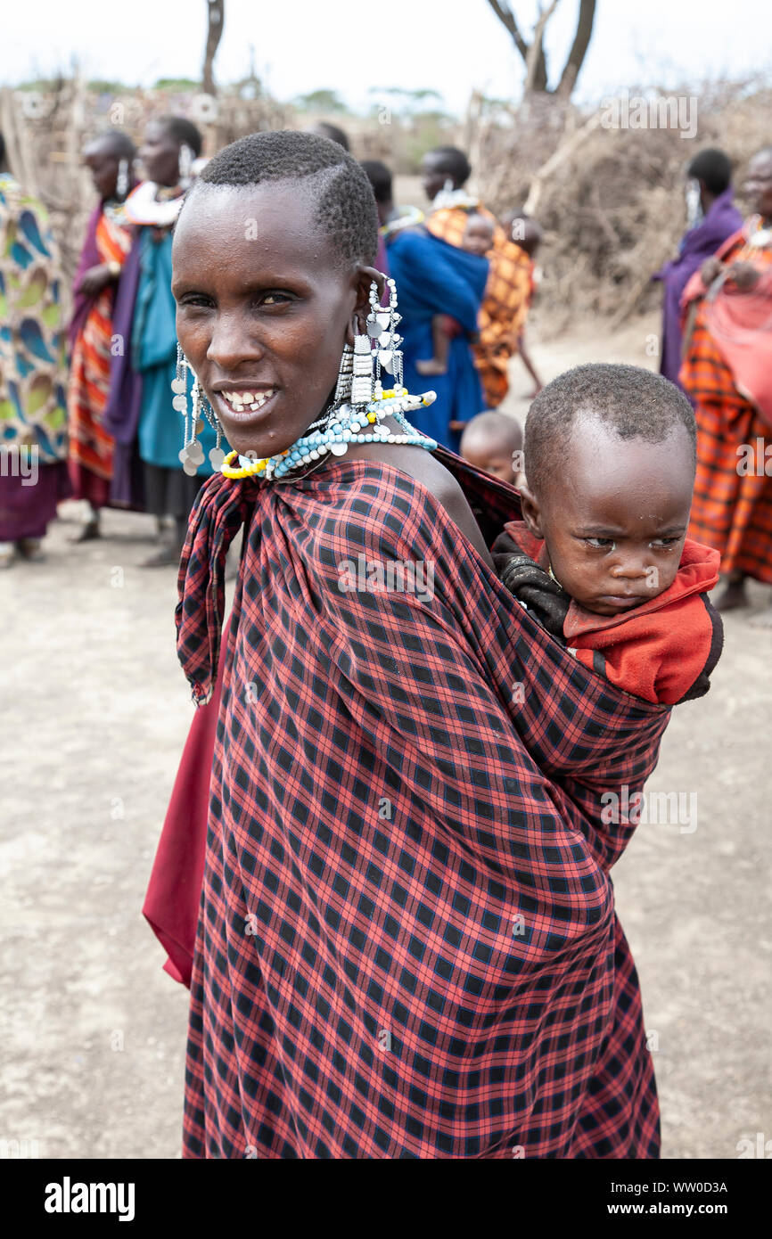 Maasai Mutter mit einem kleinen Kind auf dem Rücken in einem Maasai Kraal in Tansania Stockfoto