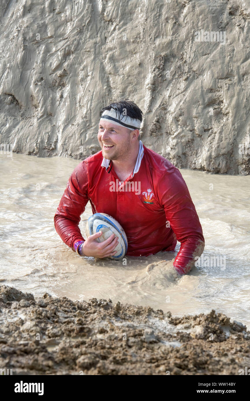 Ein Wettbewerber gekleidet als Wales Rugby Player auf der 'Mud Mile' an der haltbaren Mudder Ausdauer Event im Badminton Park, Gloucestershire, Großbritannien Stockfoto